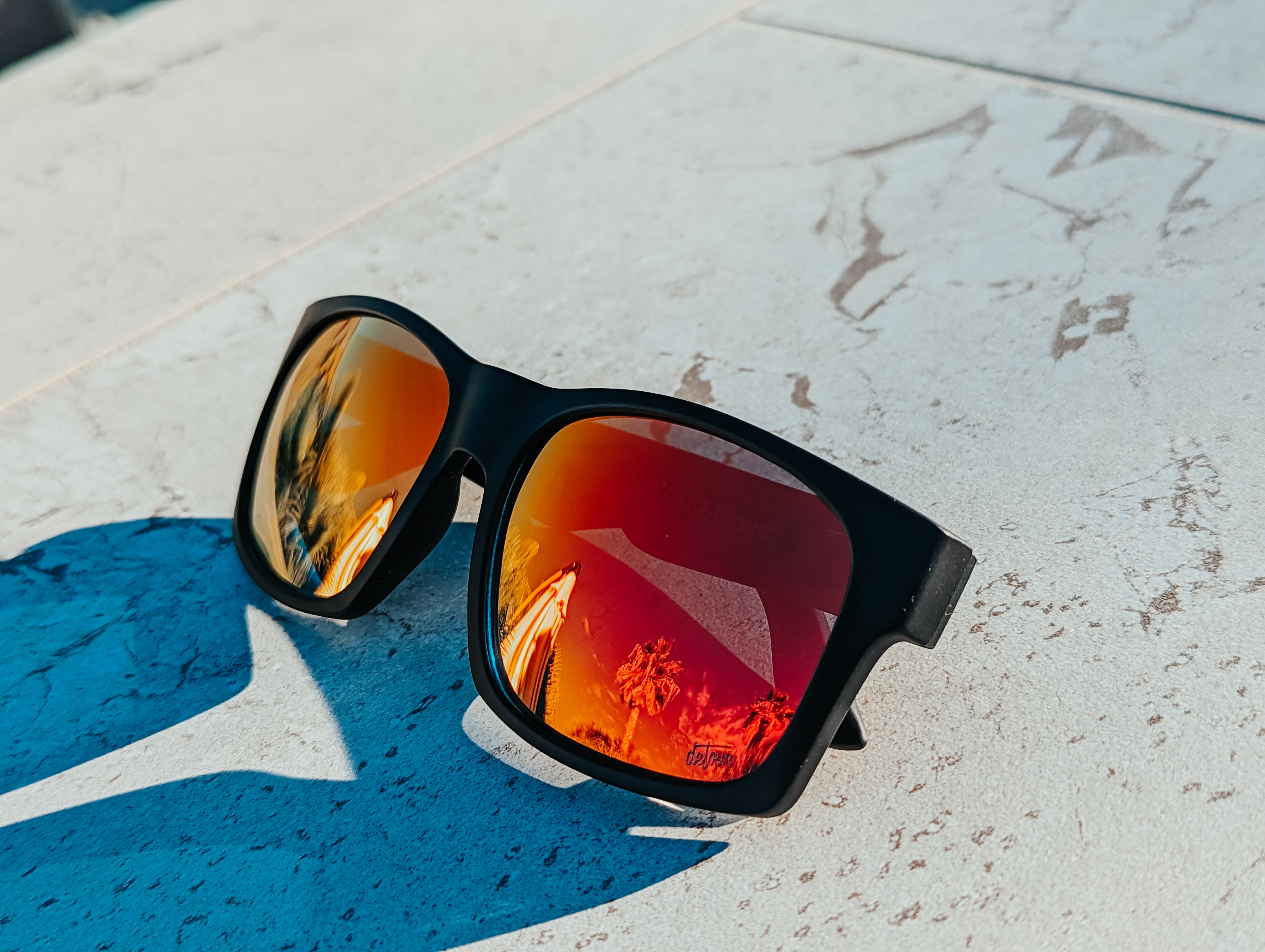 Man wearing mirrored goggles and gray beanie, holding skis in a snowy setting.