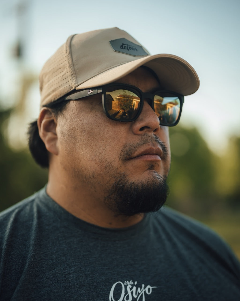 Man wearing mirrored goggles and gray beanie, holding skis in a snowy setting.