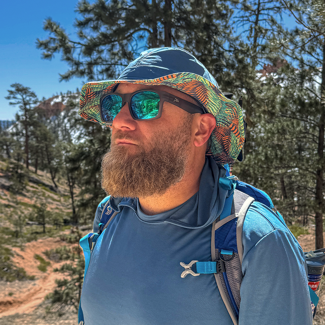 Man wearing mirrored goggles and gray beanie, holding skis in a snowy setting.