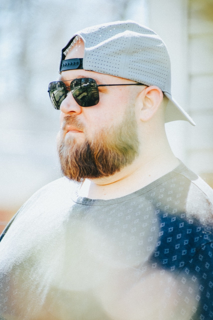 Man wearing mirrored goggles and gray beanie, holding skis in a snowy setting.