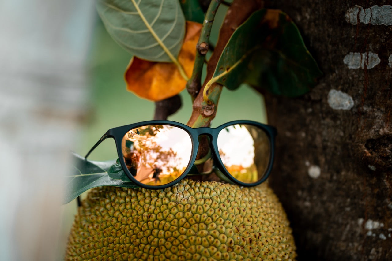 Man wearing mirrored goggles and gray beanie, holding skis in a snowy setting.