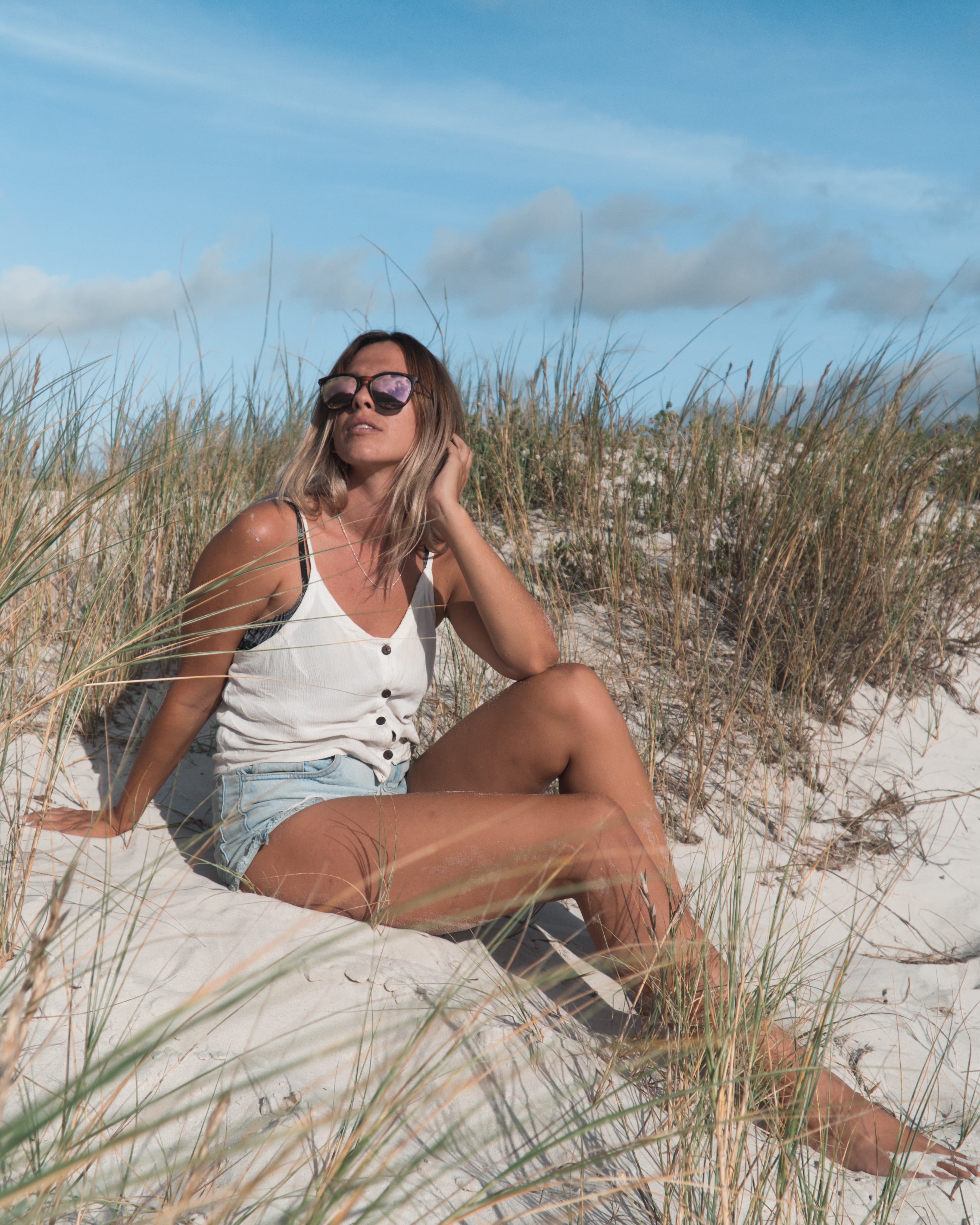 Man wearing mirrored goggles and gray beanie, holding skis in a snowy setting.