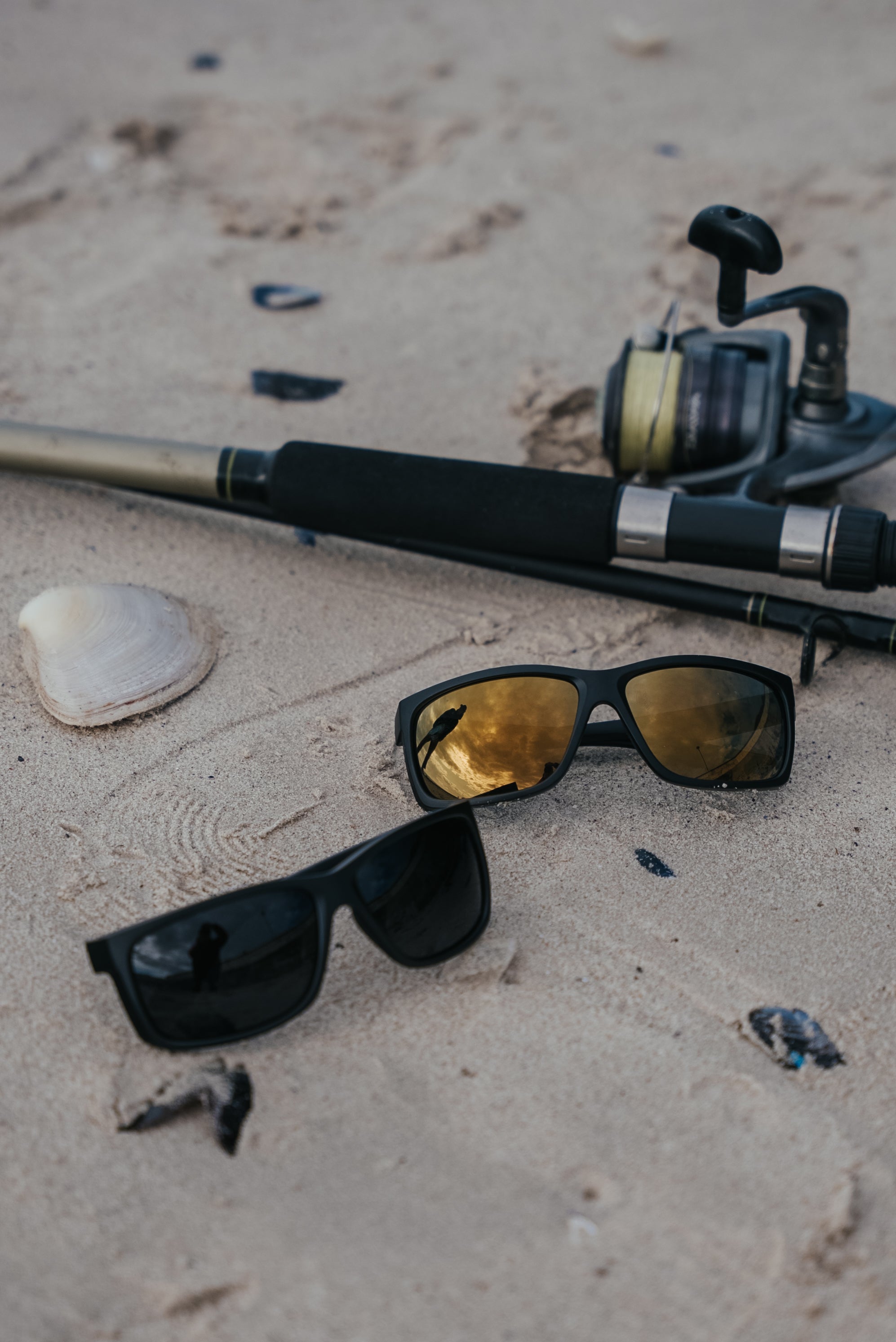 Man wearing mirrored goggles and gray beanie, holding skis in a snowy setting.