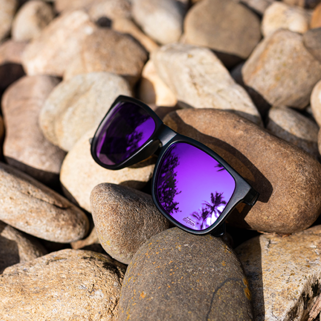 Man wearing mirrored goggles and gray beanie, holding skis in a snowy setting.
