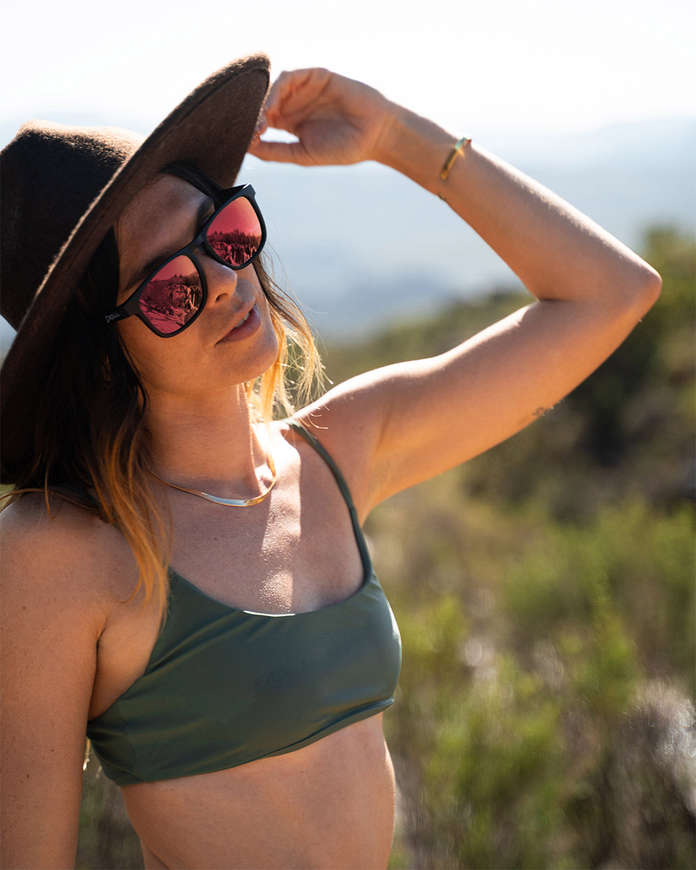 Man wearing mirrored goggles and gray beanie, holding skis in a snowy setting.