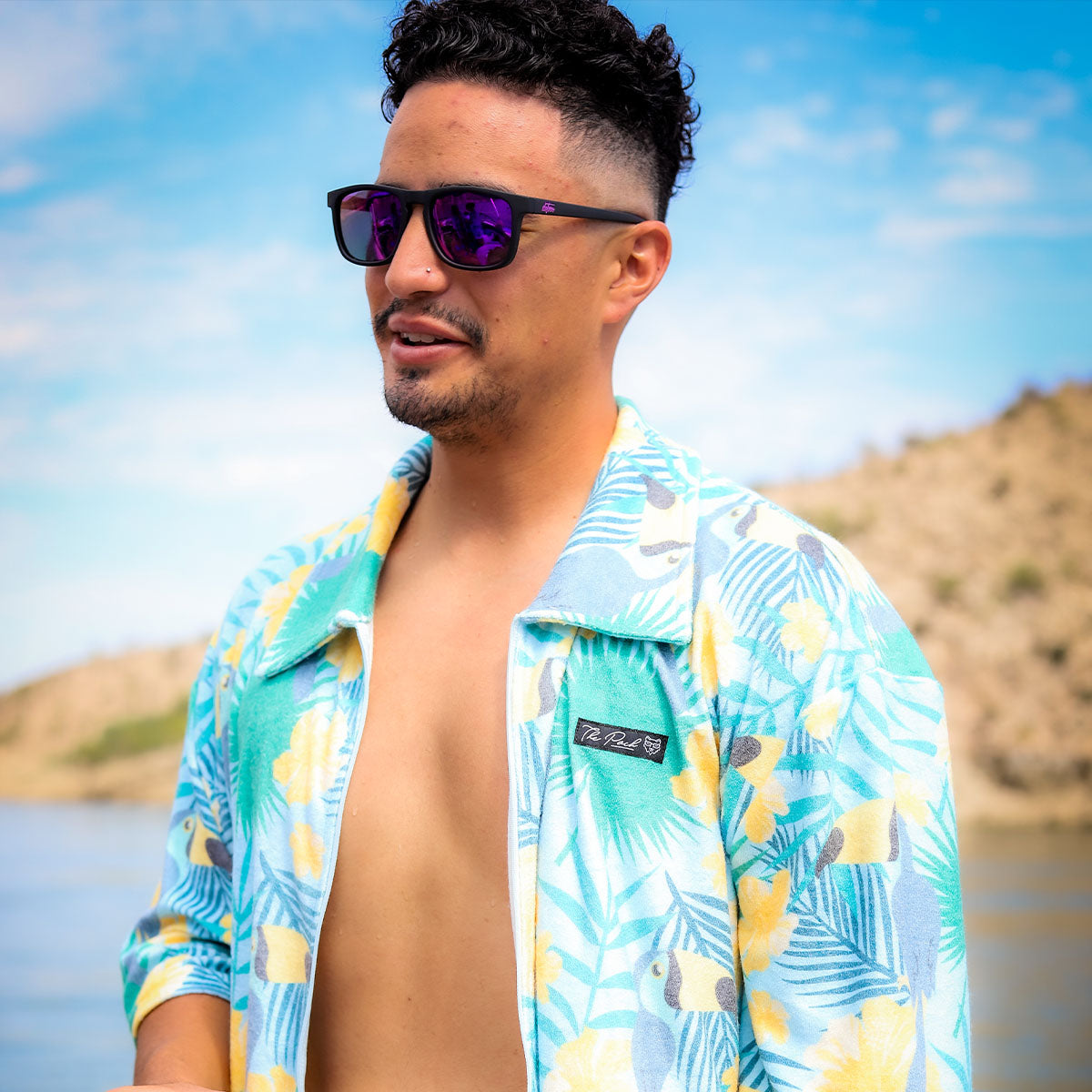 Man wearing mirrored goggles and gray beanie, holding skis in a snowy setting.
