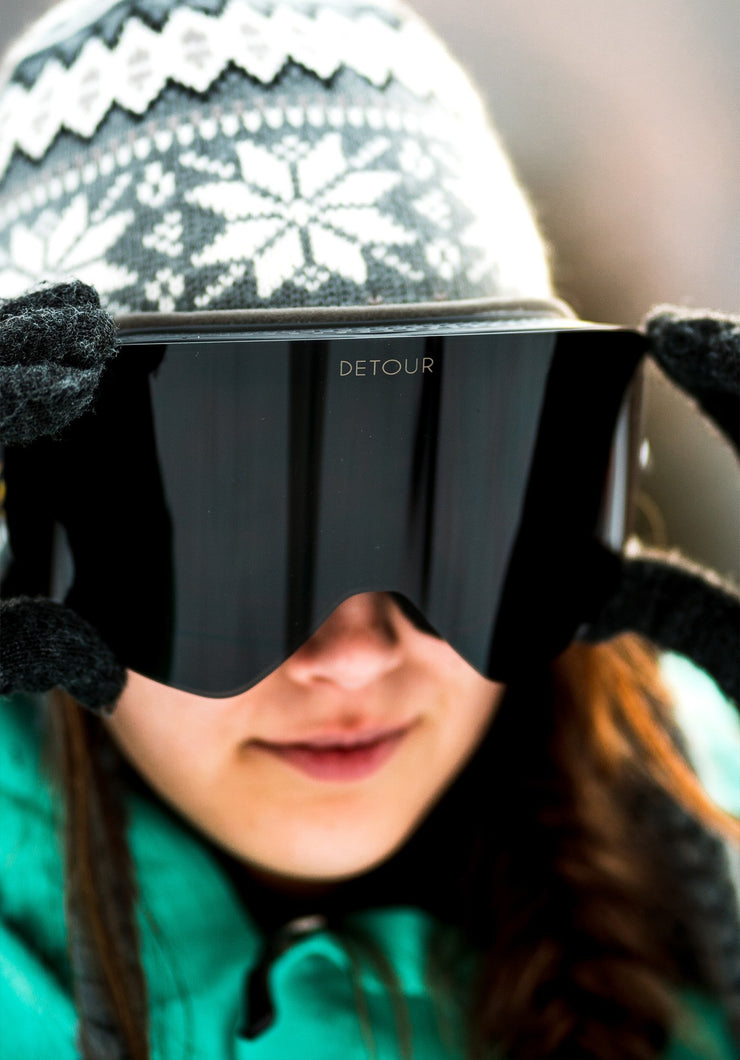 Woman wears black Detour magnetic snow goggles for skiing